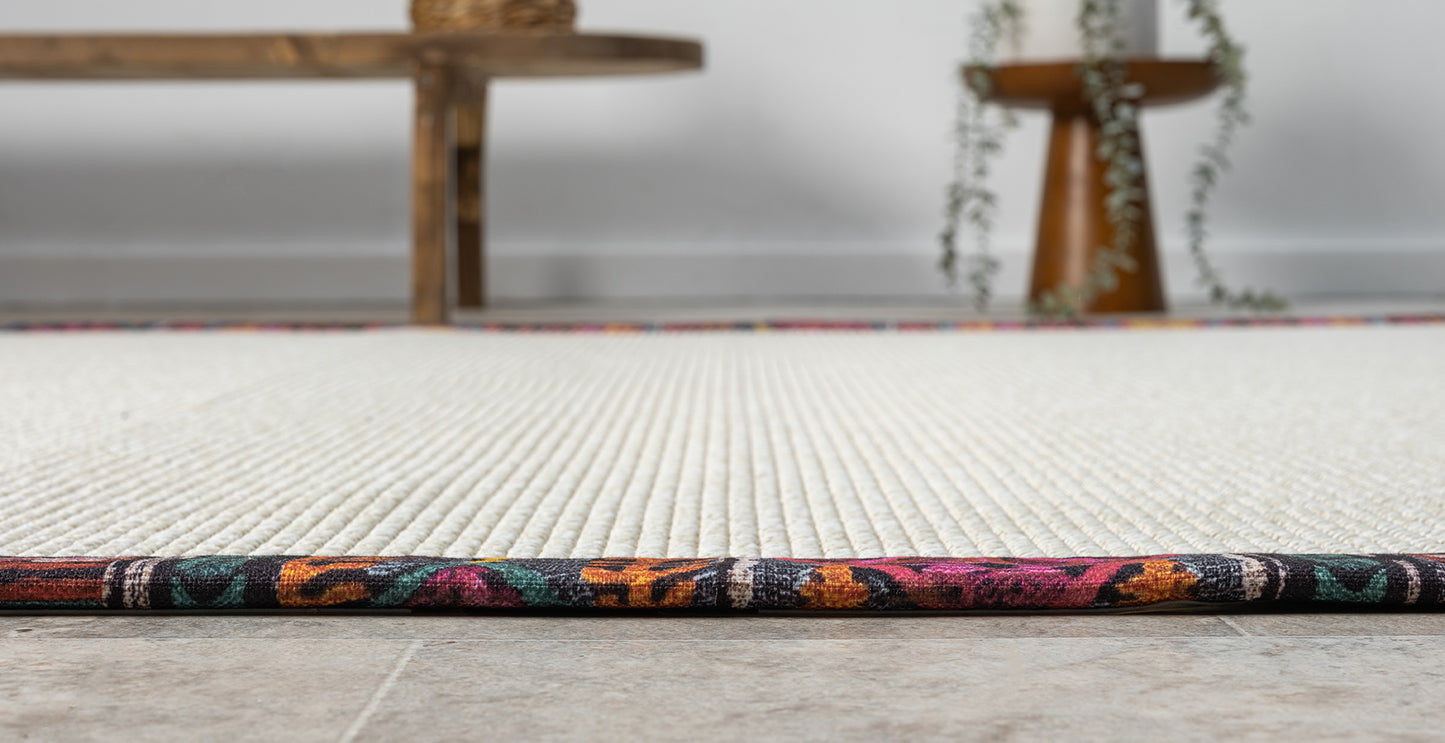 Minimalist bir yaşam alanında serilmiş, el yapımı kumaş bordürlü sisal halının detayı ve estetik görünümü.