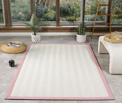 HALI VAGONU'nun el yapımı pembe kumaş bordürlü krem sisal halısı, doğal bir ortamda sergileniyor. Bu dayanıklı sisal halı, yüksek kaliteli yapısıyla dikkat çekerken, modern salon ve ofisler için şık bir zemin kaplaması sağlıyor. Evcil hayvan dostu özellikleriyle, kolay temizlenebilir bir alternatif sunar. İşte bu krem sisal halı, el yapımı ve dekoratif özellikleriyle hemen göze çarpıyor.