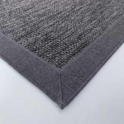 Gri sisal halının detaylı bir görüntüsü, kenarında kumaş bordürü ile modern bir görünüm sunuyor.
