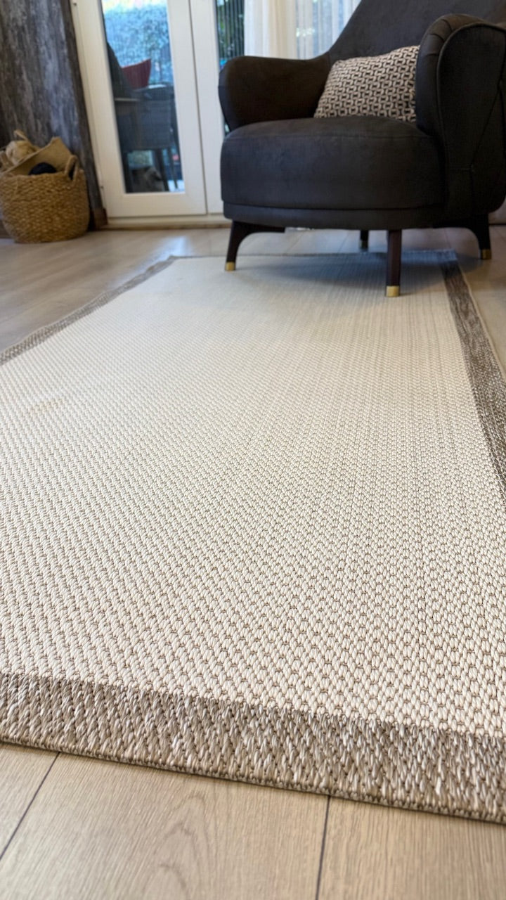 Uzak açıdan çekilmiş bir Siesta sisal halı, şezlongun önünde temiz ve modern bir görünüm sunuyor.