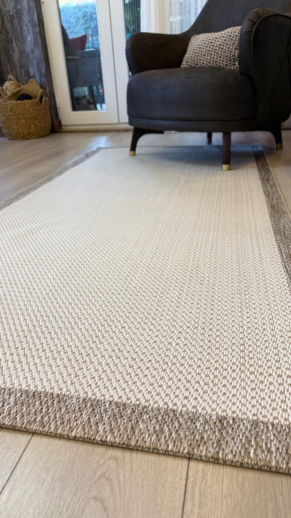Uzak açıdan çekilmiş bir Siesta sisal halı, şezlongun önünde temiz ve modern bir görünüm sunuyor.