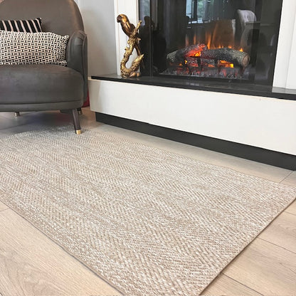 Sisal halı, modern bir şalı oturma alanına estetik katıyor. Arkada dekoratif bir şömine görülüyor.